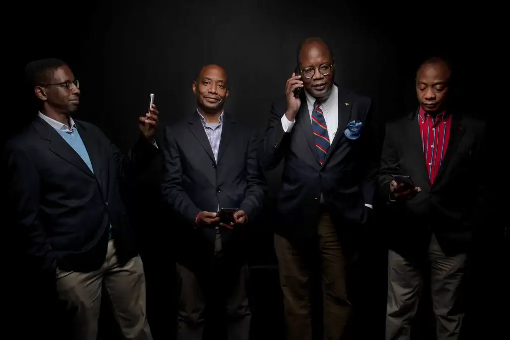 Four professional businessmen in suits posing against a black studio background, representing team branding and executive corporate identity