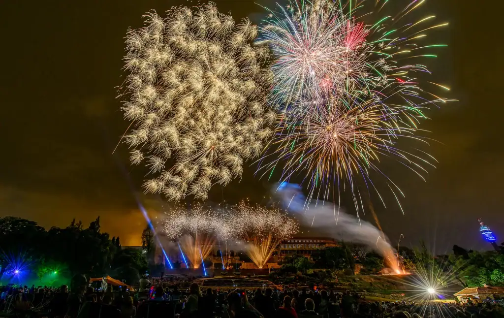 Spectacular fireworks light up the night sky during an outdoor event in Johannesburg with crowd watching