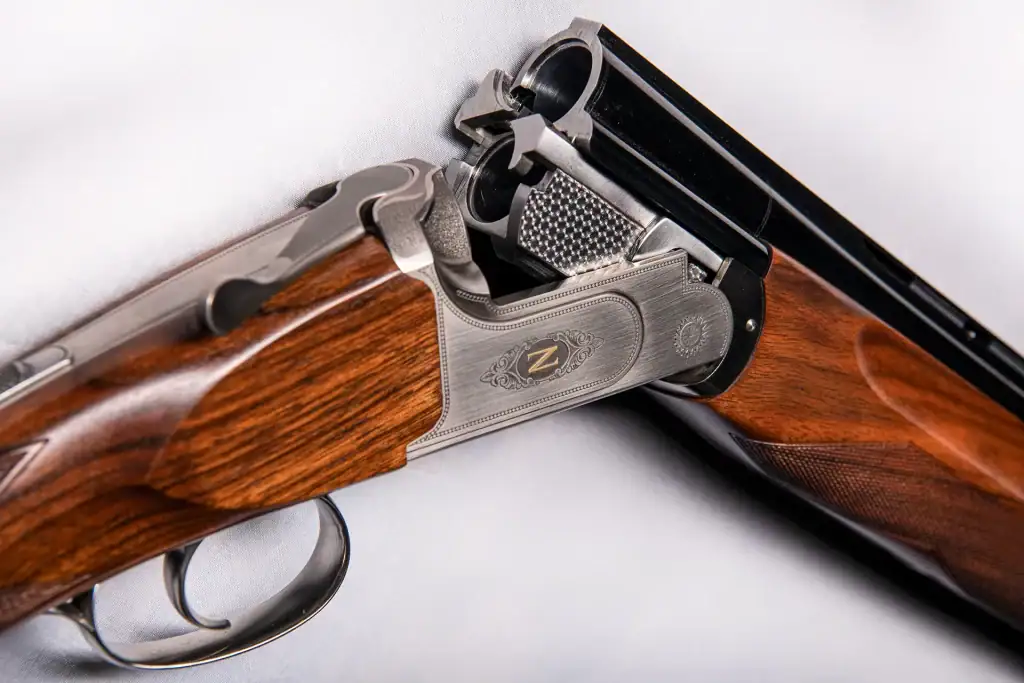 Close-up of a luxury over-under shotgun featuring detailed silver engraving and polished wood stock by Z Gun in the product photography image