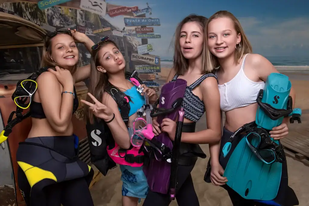 Four teen girls posing with snorkels and fins during a beach-themed scuba birthday party, perfect for youth event and lifestyle photography