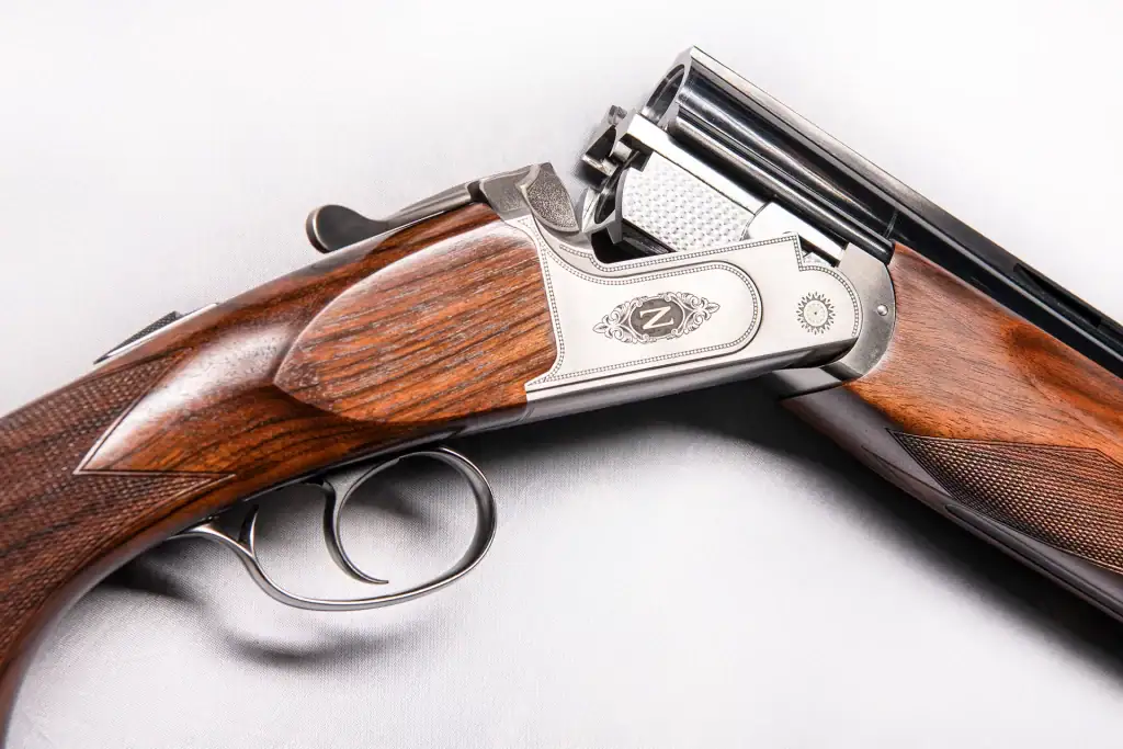 Product Photography of a luxury Z Gun over-under shotgun showcasing silver engraving and double trigger mechanism with polished walnut stock