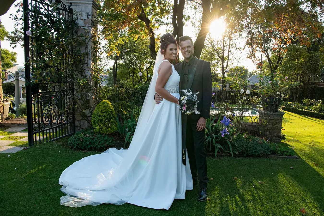 Bride and groom standing together in a sunlit garden