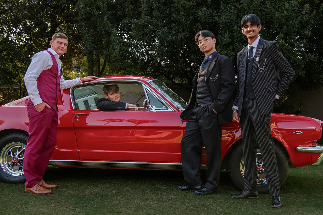 Group of matric farewell friends in formal suits photographed with a red Mustang in Johannesburg