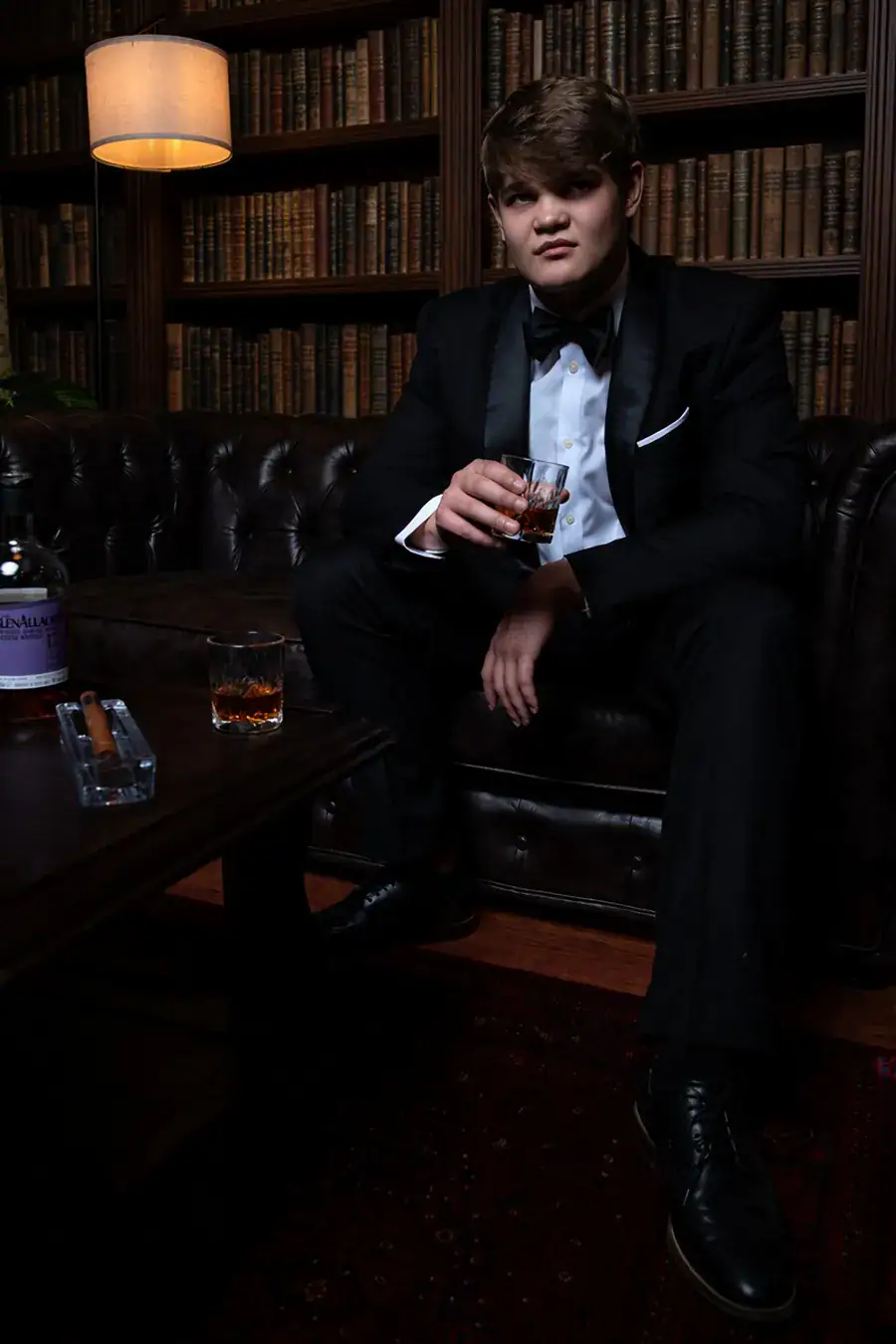 Matric farewell student in a black tuxedo seated in a dark library setting in Johannesburg