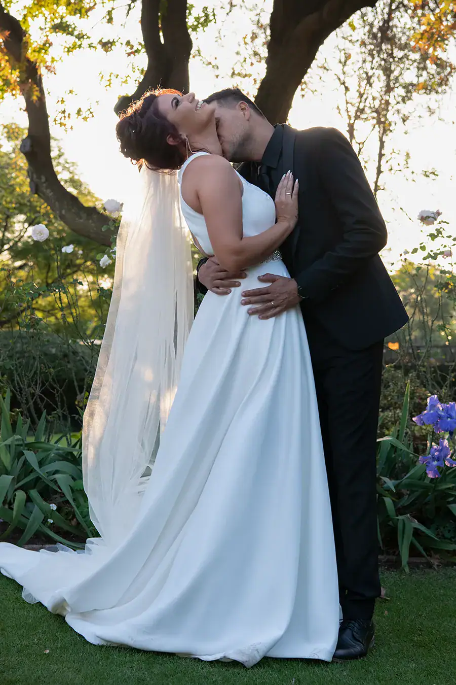 Bride and groom kissing beneath a tree during their wedding