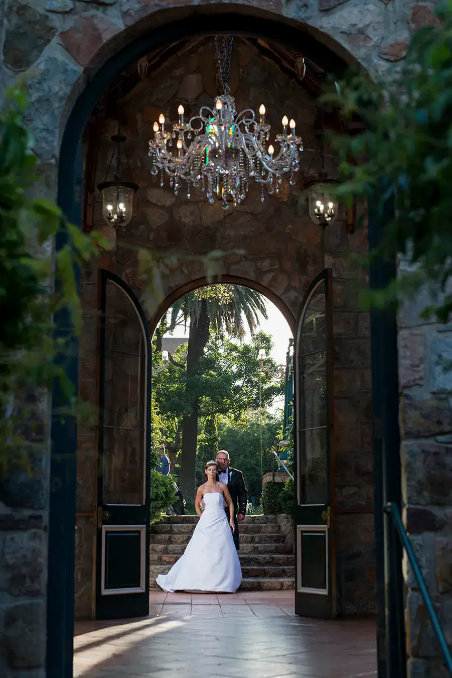 Bride and groom photographed beneath an ornate stone archway at their wedding venue
